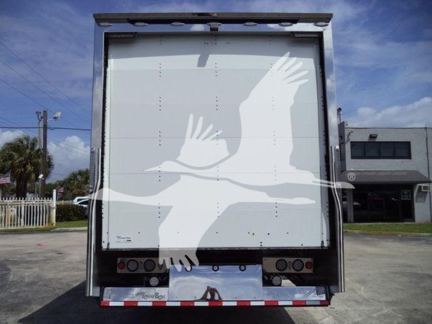 Back of a rollback truck trailer with a white dove graphic, taillights, and reflective strips visible.