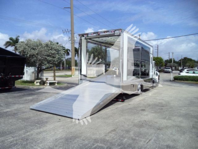 Truck bed with hydraulic ramp and enclosed cab showing empty interior and rear ramp platform extended.