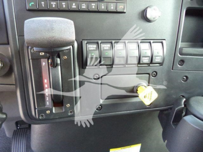 Cab interior of a 2027 International MV rollback truck showing gear shifter, control switches, and ignition key slot.