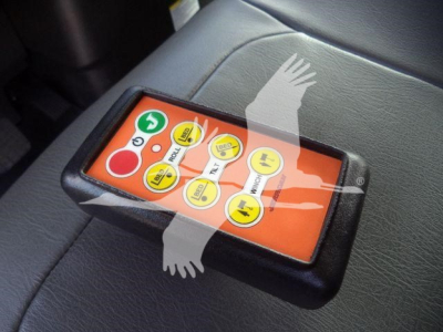 Control module with orange face showing multiple yellow buttons and green power symbol on a truck seat.
