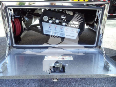 Trucks equipment: control panel with gauges and hoses inside a rear storage area; metal platform with safety labels and a control box mounted inside the truck bed.