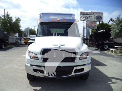 Truck front view showing International MV model cab, white exterior, grille, headlights, and bumper in a dealership lot.