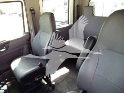 Interior of a 2027 International MV rollback truck showing two front seats and partial rear seating with gray upholstery.