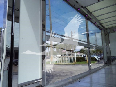 Interior view of a new 2027 International MV rollback truck showroom with glass walls and reflections.