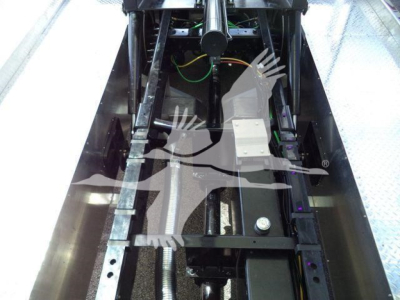 Truck chassis showing internal mechanism and rails with wiring harness; no legible labels or text clearly visible.