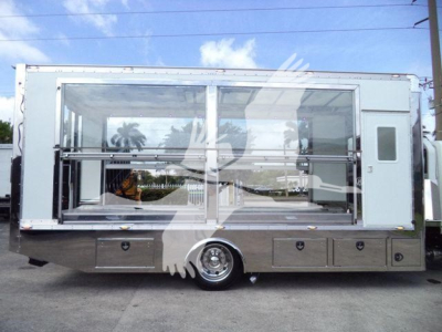 Truck body side view showing large glass display with metal frame, storage drawers under, and wheel in center; International MV rollback unit.