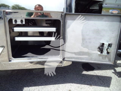 International MV rollback truck storage compartment with chrome shelves and metal door.