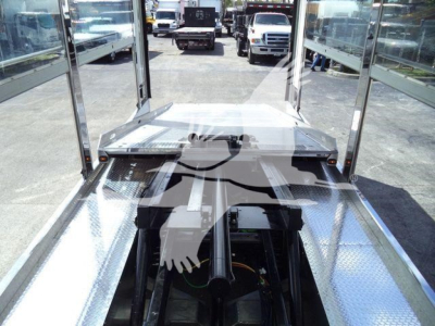 Truck trailer platform showing aluminum flooring and rear hitch with metal step, long wheelbase, and cab visible in background.