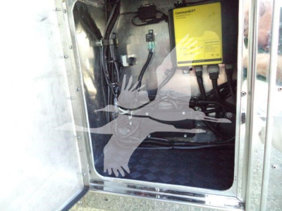 Trucks equipment bay showing a CommandUPT device with yellow label mounted inside a compartment; cables and connectors visible.