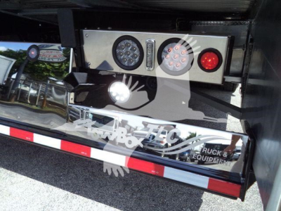 Truck rear showing LED work lights and control panel on hydraulic rollback equipment mounting area.