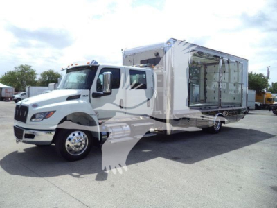 Truck in a rollback configuration with a large white cab and open side panel showing interior storage area.