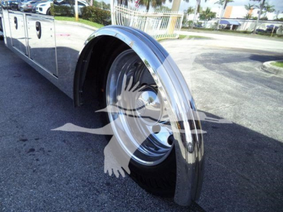Truck rear wheel and chrome fender at a rollback truck body showing polished wheel and fender; reflections on chrome surface.