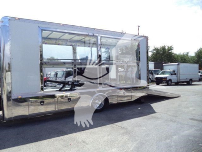 Large white crew cab rollback truck with side awning and interior seating visible through windows.