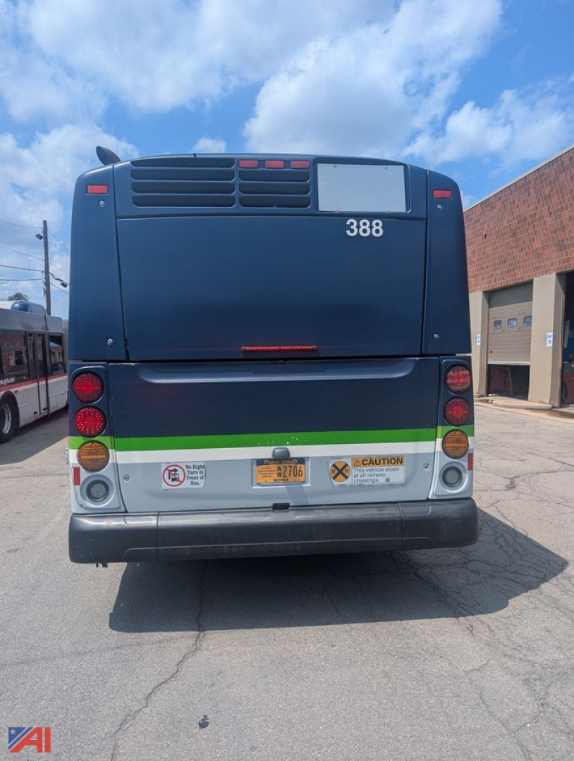 Rear view of a 2013 New Flyer XD60 transit bus showing license plate area, taillights, rear bumper, and safety decals.