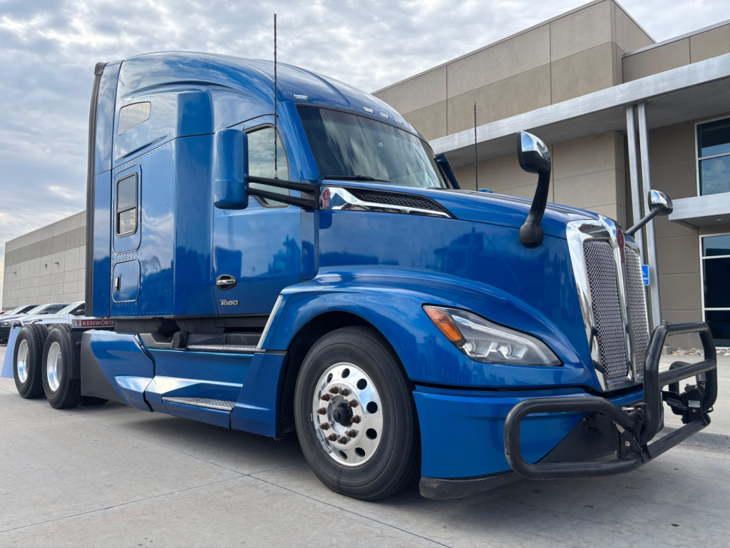Kenworth T680 truck in blue, side view showing front bumper guard, sleeper cab, and dual rear wheels.
