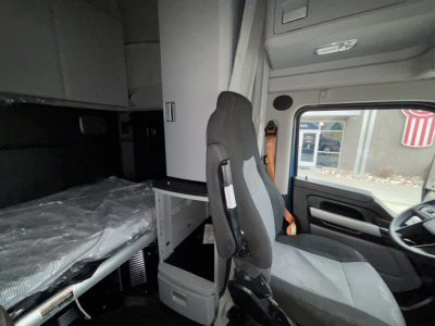 Interior of a Kenworth T680 cab showing sleeper area with bunk, cabinet, and driver seat. Text not clearly legible beyond interior fixtures.