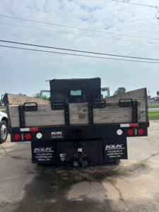 Kenworth T280 rear view showing cargo bed and bumper with company logos and contact numbers.