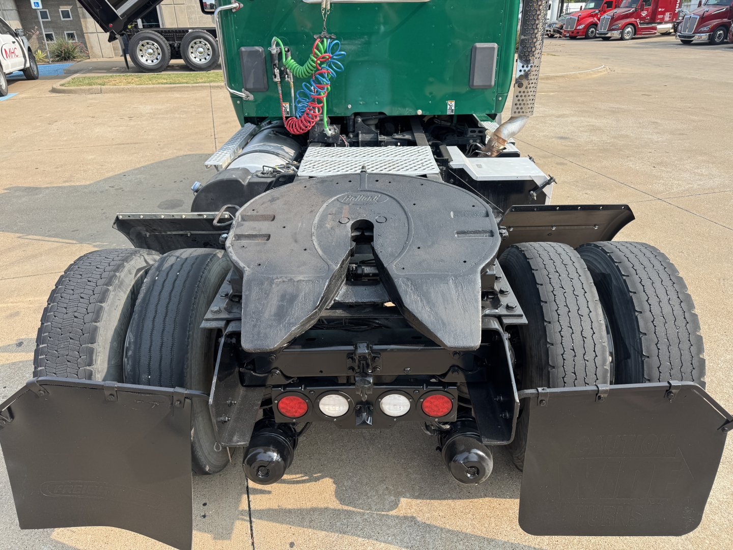 Kenworth T880 rear view showing fifth wheel, dual rear axles, mudflaps, and various hoses and air lines visible.