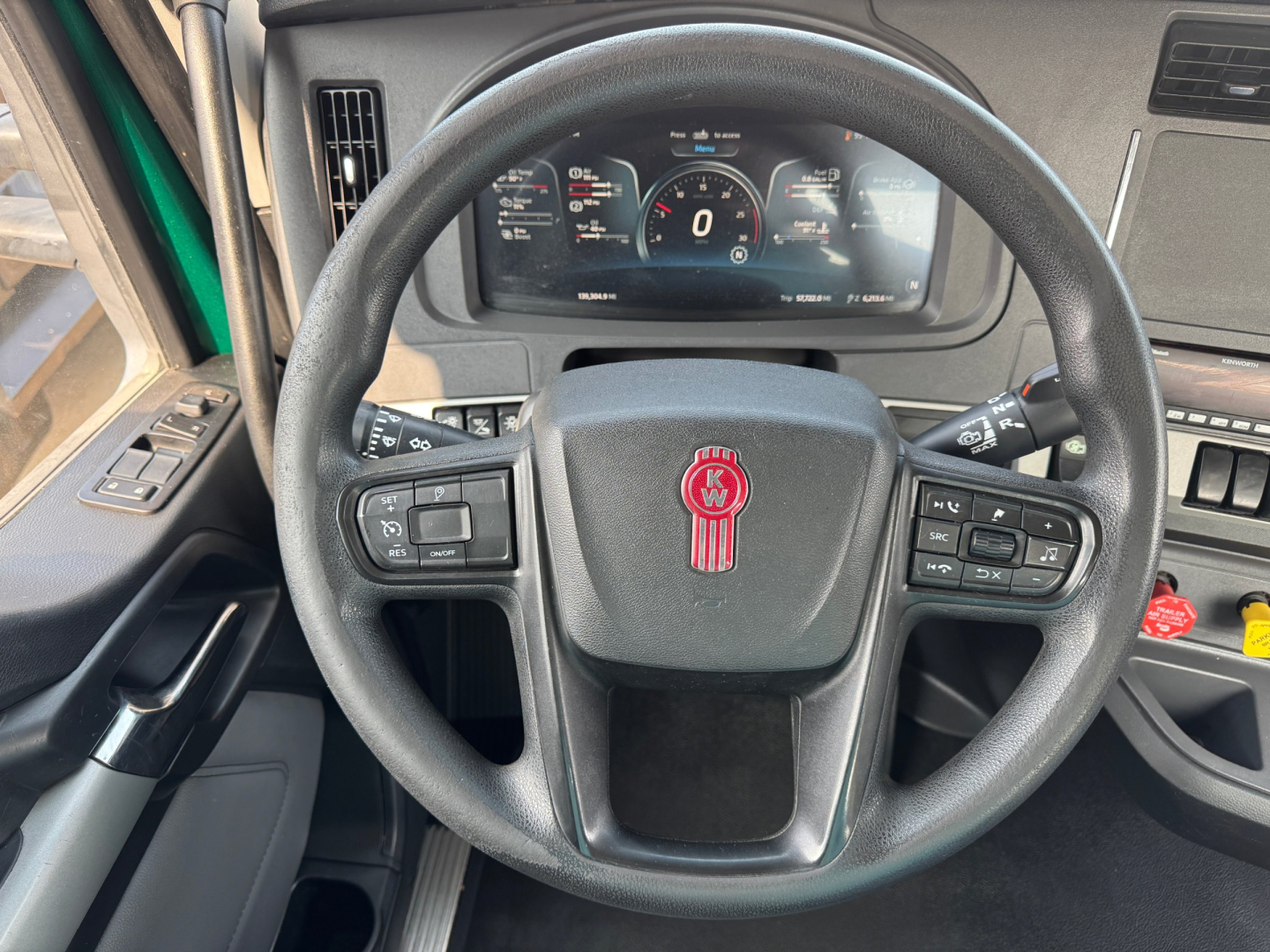 Kenworth T880 cab interior showing steering wheel and instrument cluster with tachometer and gauges.
