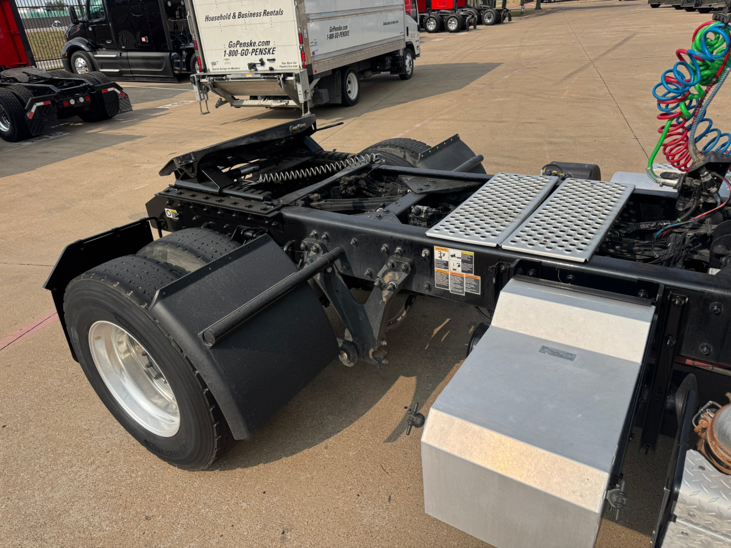 Kenworth T880 tractor rear chassis showing fifth wheel mount and air lines with aluminum toolbox and steps.