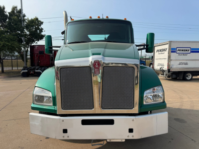 Kenworth T880 front view showing large chrome grille, green cab, white bumper, square headlights, and clearance lights on roof.
