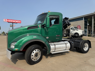 Kenworth T880 semi truck in green cab with dump bed, side view showing fuel tanks and rear chassis.
