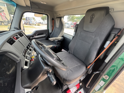 Kenworth T880 truck interior showing driver seat and steering wheel with dashboard and passenger seat. Visible are command controls, steering column, and gear lever.