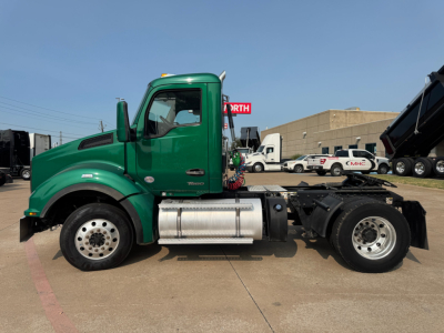 Kenworth T880 side view showing green cab, fuel tanks, and chassis with a logo on door and reflective strips. No specific model text visible in image.