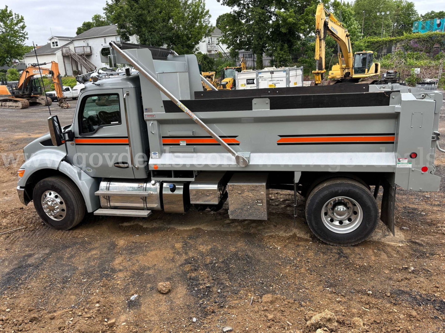 Kenworth T380 dump truck side view showing dump bed, cab, and chrome steps with side rails; gray paint with orange stripe.