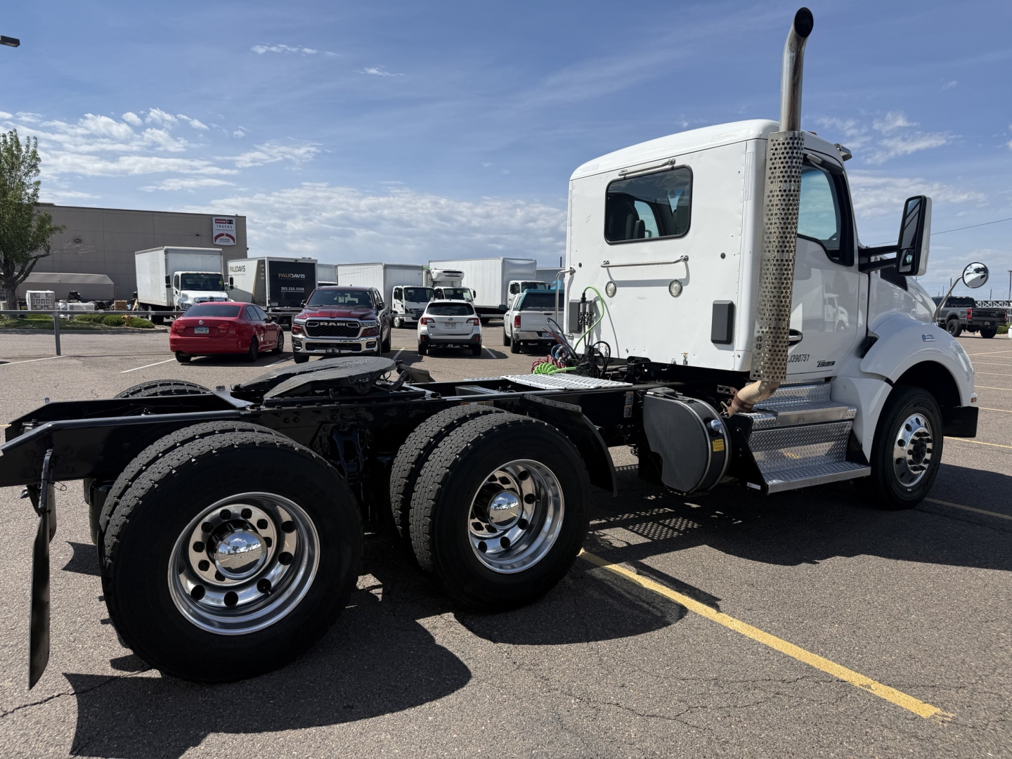 Kenworth T880 chassis in white cab with dual rear axles and exhaust stack visible in a parking lot.