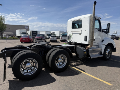 Kenworth T880 chassis in white cab with dual rear axles and exhaust stack visible in a parking lot.