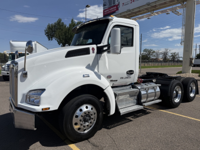 Kenworth T880 conventional daycab truck in white, side view with chrome fuel tanks, dual rear axles, front grille, and large mirrors.