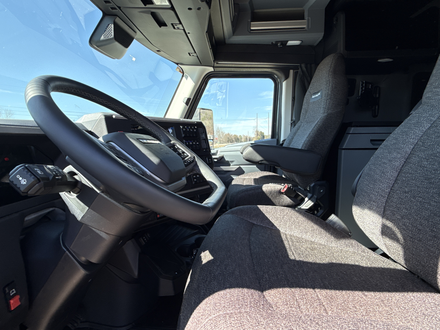 Cab interior of a 2026 Mack PR64T76H truck showing driver seat, steering wheel, dashboard, and passenger seat