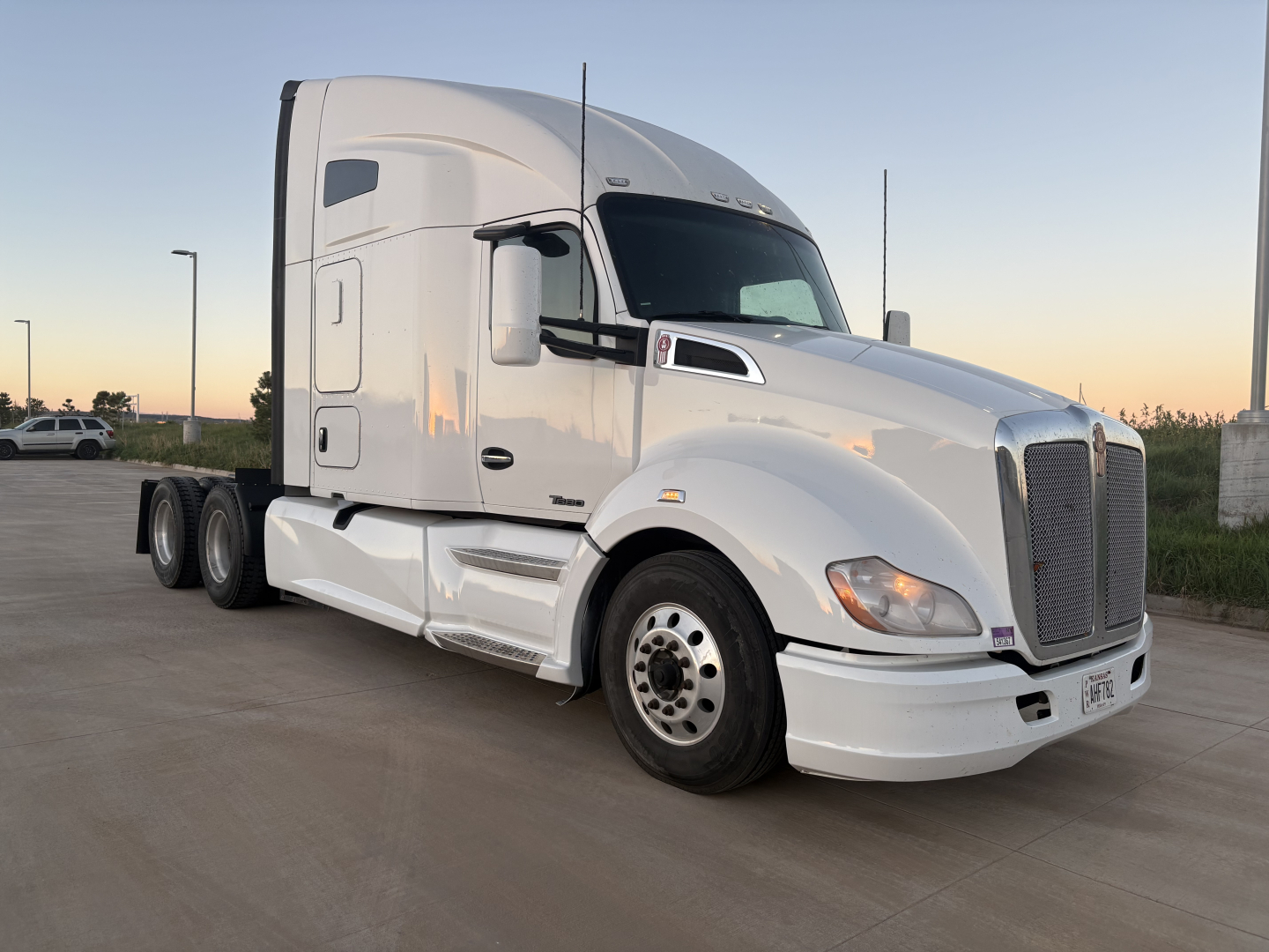 Kenworth T680 tractor in white, side view showing sleeper cab, front grille, and dual rear axles.
