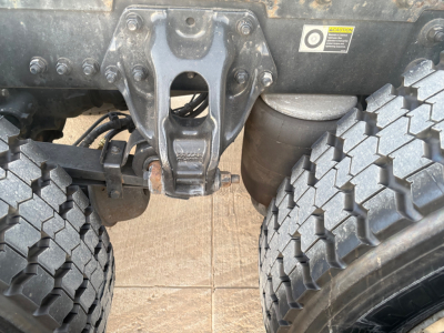 Kenworth T680 chassis view showing tag, rear suspension hanger, and dual rear tires with heavy tread.