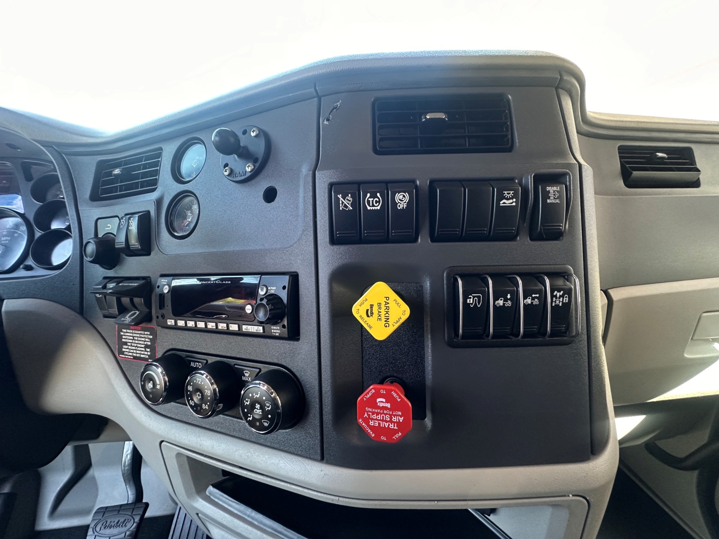 Truck dashboard with controls and switches, Peterbilt badge area not visible, center cluster showing gauges and knobs.
