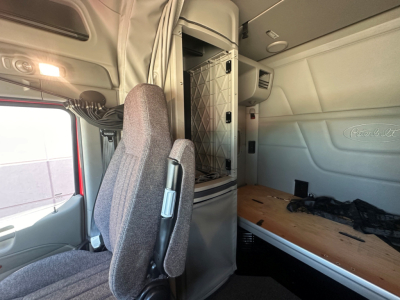 Peterbilt 579 truck interior sleeper cab area with bunk bed and partition, driver seat and side window visible.