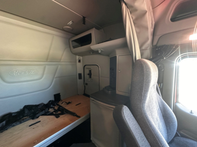 Peterbilt 579 truck interior sleeper cab with bunk and cockpit seating, overhead storage, and window view.