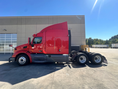 Peterbilt 579 tractor in red cab, side view, with sleeper, chrome wheels, and fifth wheel mounting.