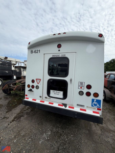 Ford E450 bus rear showing emergency exit doors, handicap placard, B-621 number, and various tail lights.