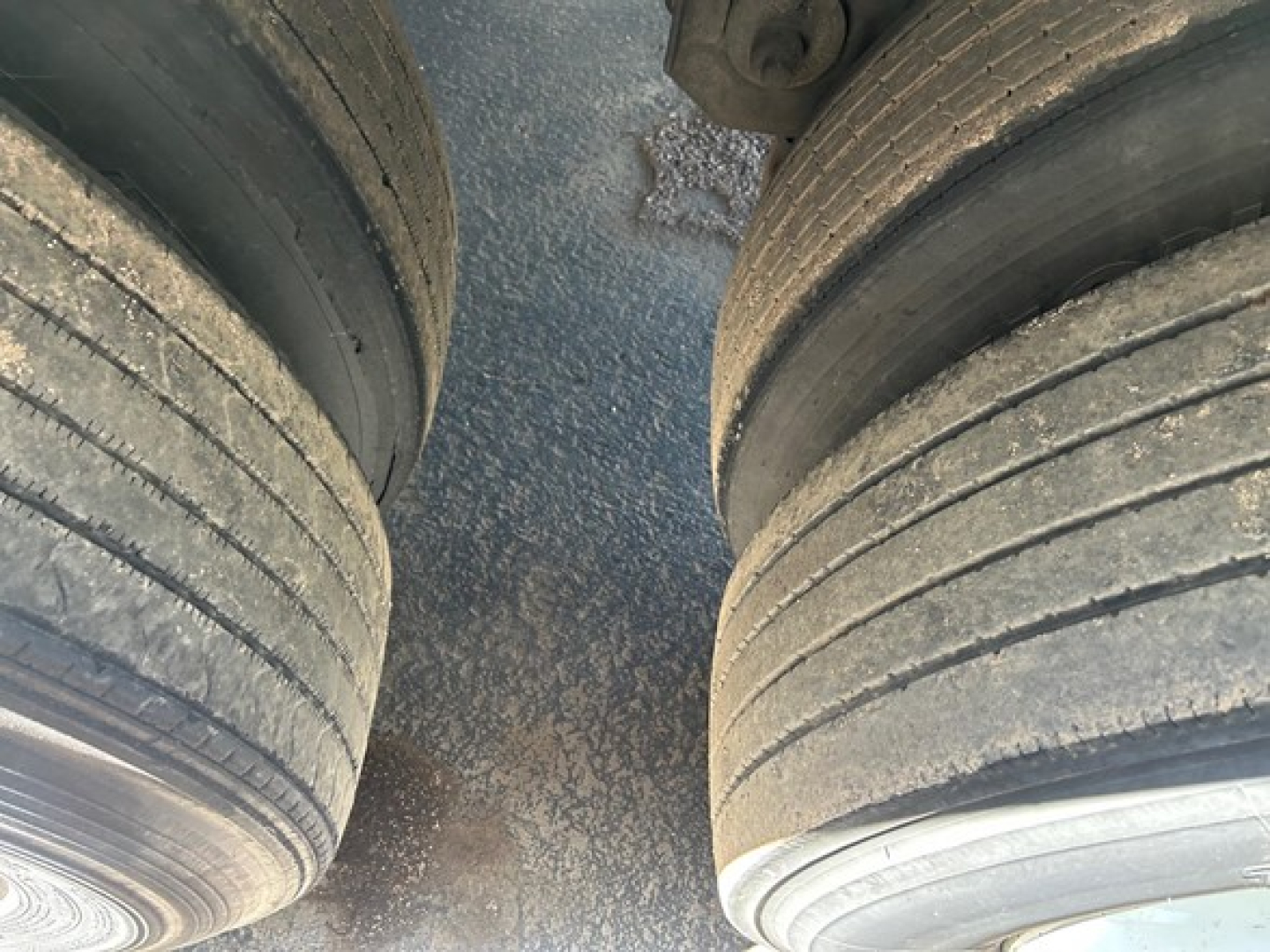 Dual rear tractor tires of a 2018 Utility 3000R W trailer showing tread and mud, viewed from between wheels.