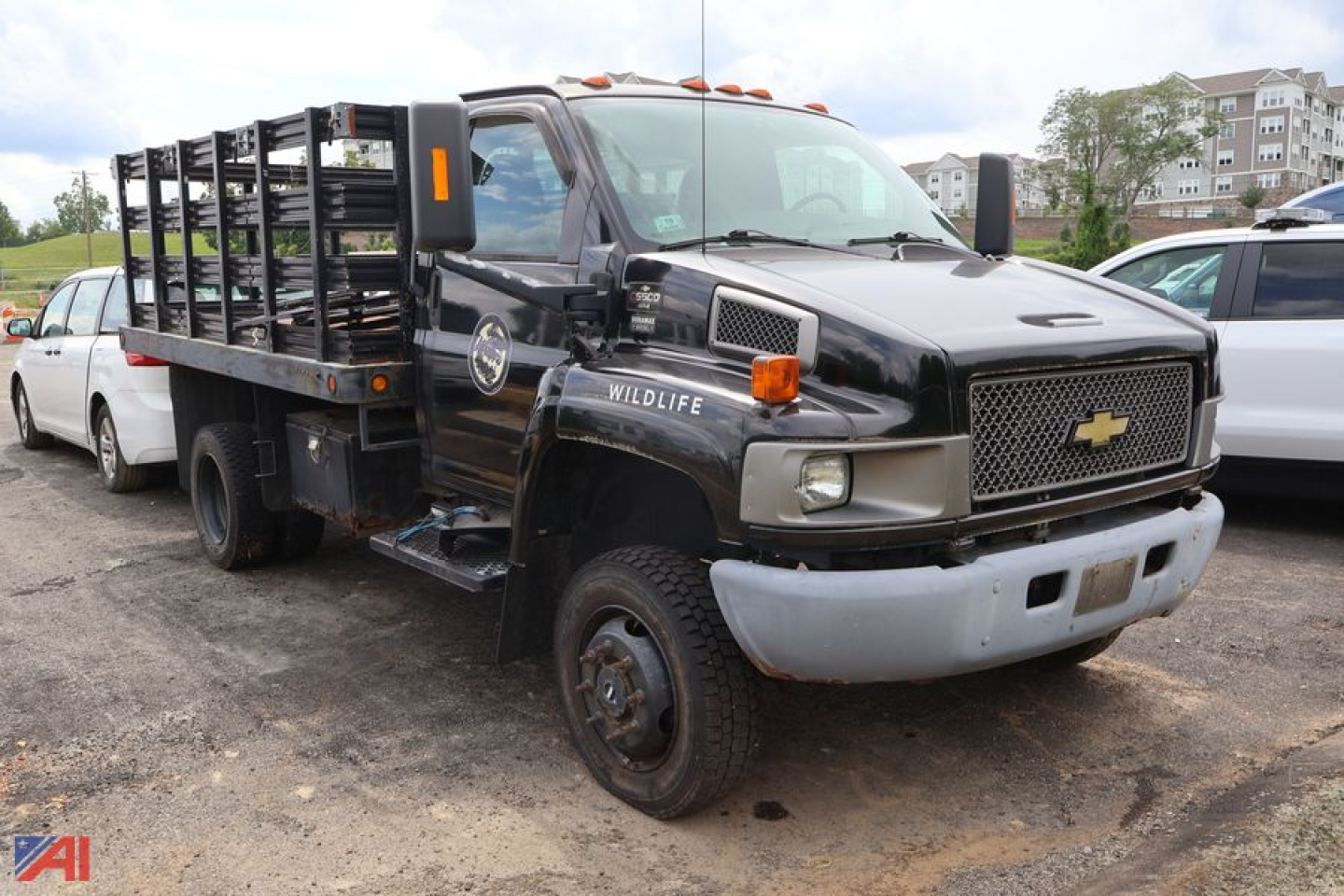 Chevrolet medium-duty dump truck in service showing front grille and stacked stake bed with Wildlife emblem and Chevrolets badge