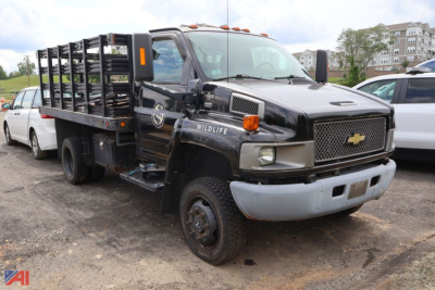 Chevrolet medium-duty dump truck in service showing front grille and stacked stake bed with Wildlife emblem and Chevrolets badge