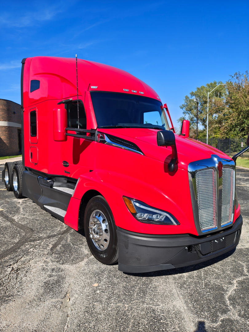 Kenworth T680 semi-truck in red, front three-quarter view showing bold chrome grille and aerodynamic hood, black bumper, and side mirrors.