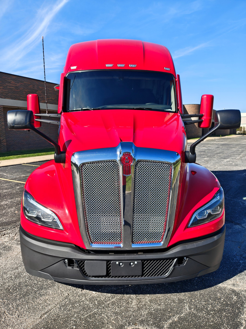 Front view of a red 2024 Kenworth T680 truck showing chrome grille, headlights, and large bumper.