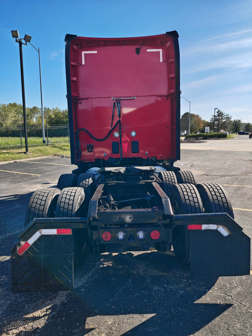 Kenworth T680 rear view showing fifth wheel, dual rear axles, and chassis; red sleeper cab with elevated stack, no trailer connected.