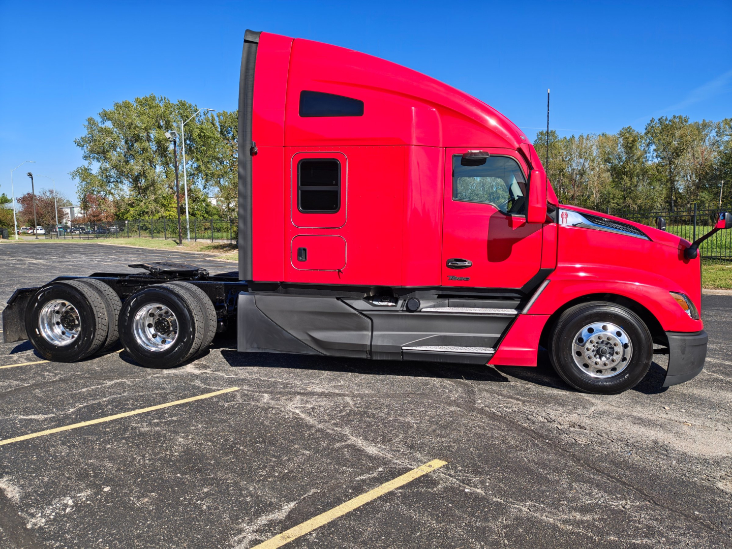 Kenworth T680 tractor trailer in red, side view showing cab and rear wheels, no visible text on panels