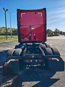 Kenworth T680 rear view showing fifth wheel, dual rear axles, and chassis; red sleeper cab with elevated stack, no trailer connected.