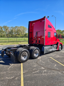 Kenworth T680 sleeper tractor in red, side view showing rear axles and wheels, roof and sleeper cabin, with clear blue sky.