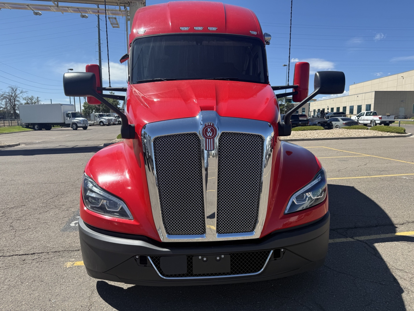 Kenworth T680 front view showing bold chrome grille and red cab.